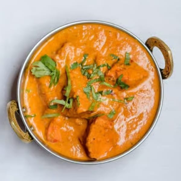 Curry House's vibrant orange chicken tikka masala, garnished with fresh cilantro in a metal bowl.